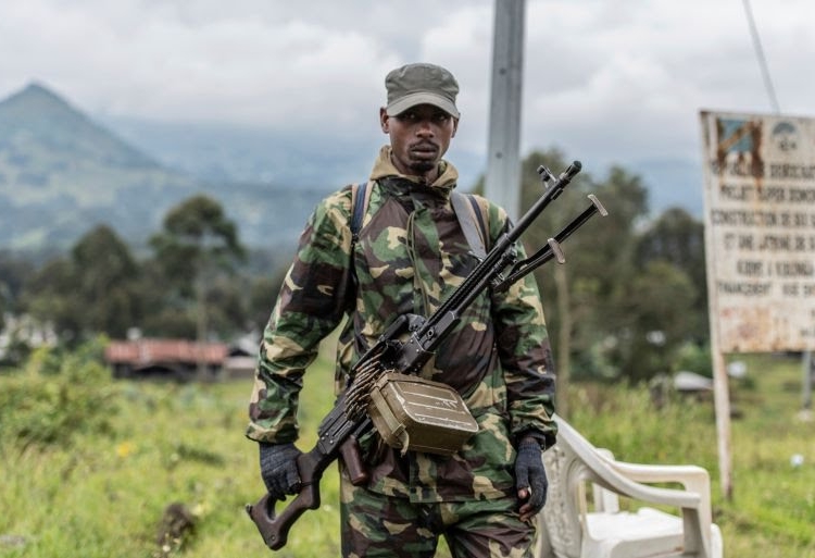 An M23 rebel stands with his weapon during a ceremony to mark the withdrawal from their positions in the town of Kibumba, in the eastern Democratic Republic of the Congo, on Friday, December 23, 2022 [Moses Sawasawa/AP Photo]