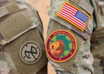 U.S. Army Sgt. Mathew Parsons (right), a signal support systems specialist, and Pfc. Jordyn Hill, an information technology specialist, both assigned to Headquarters and Headquarters Company, 27th Infantry Brigade Combat Team, New York Army National Guard, display the 27th Infantry Brigade Combat Team patch alongside the exercise African Lion patch in Tantan, Morocco, May 29, 2024. (Credit: US Military)
